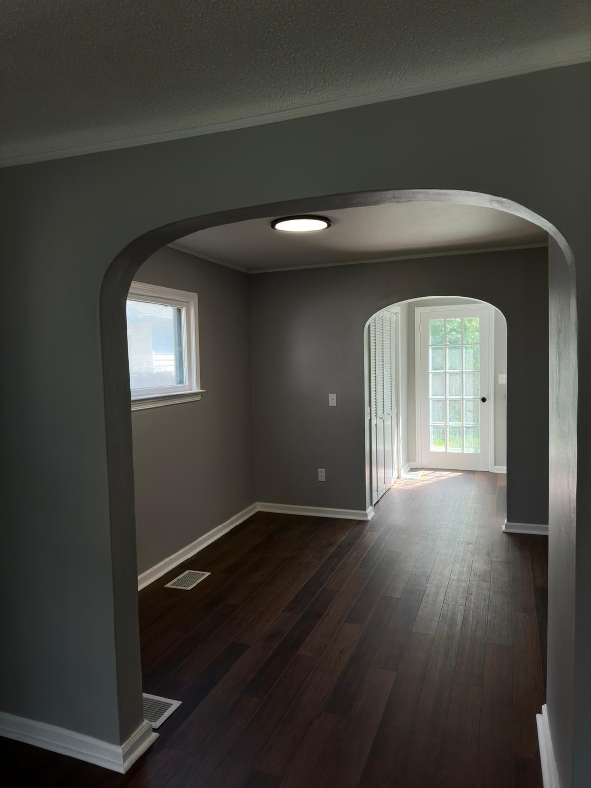 Refinished hardwood flooring flowing through an arched interior opening