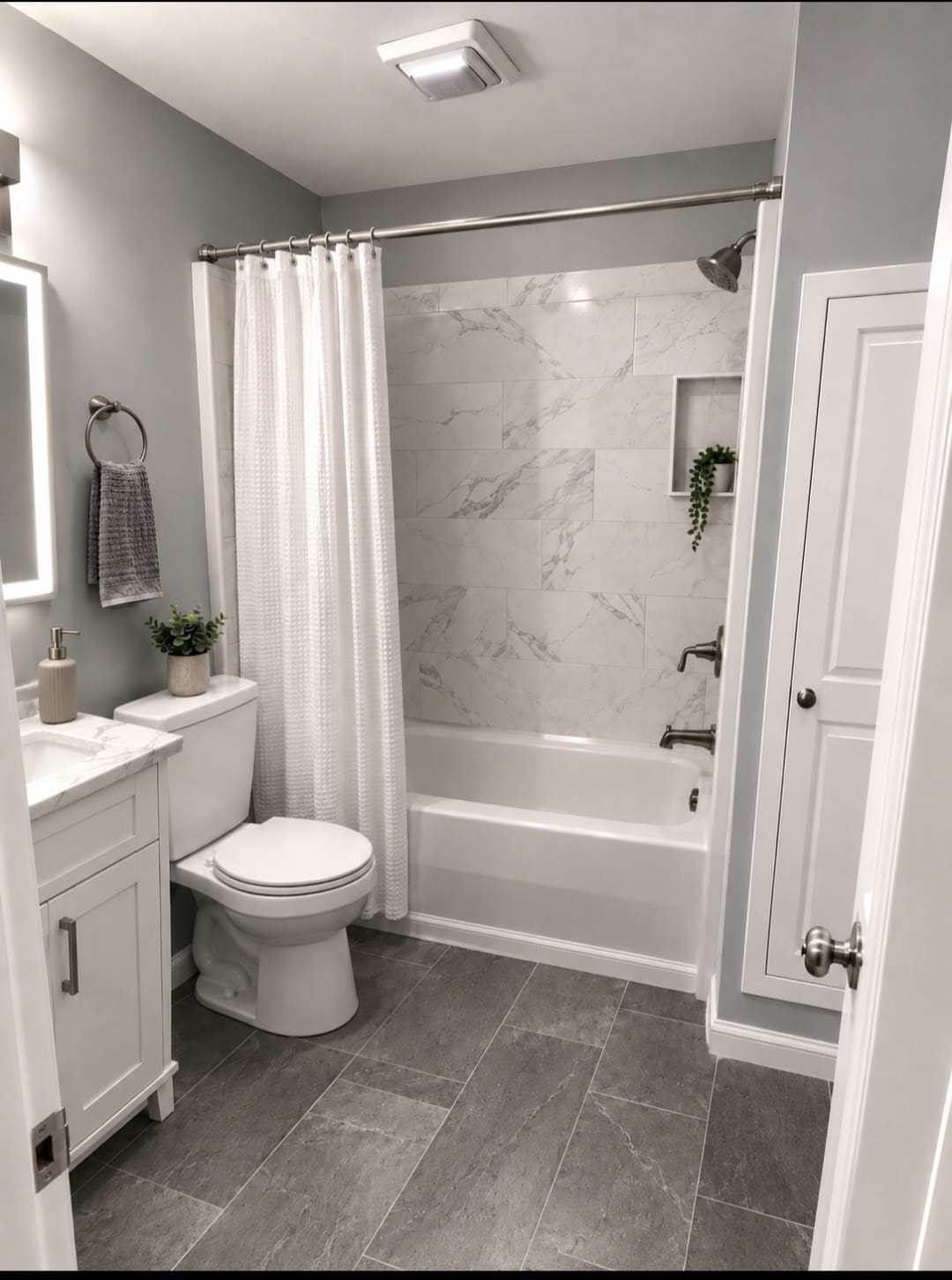 Completed bathroom with gray tile, a white vanity and marble-look tub surround