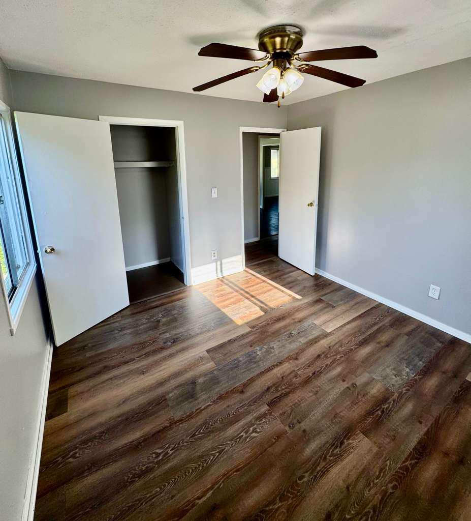 Bright bedroom with dark wood-look flooring and a double closet