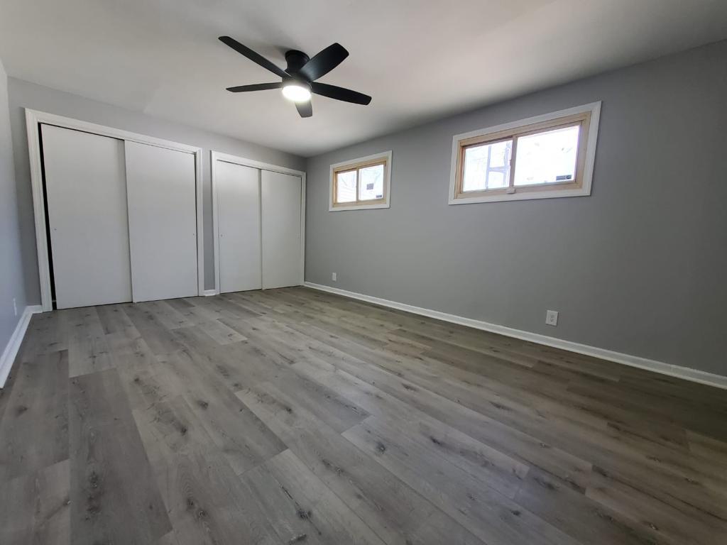 Bedroom with double closets, gray walls and new plank flooring