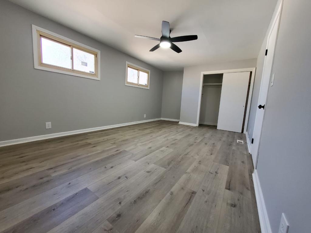 Finished bedroom with new plank flooring and high windows