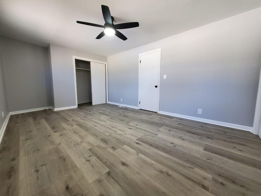 Wide view of a finished bedroom with gray walls and plank flooring