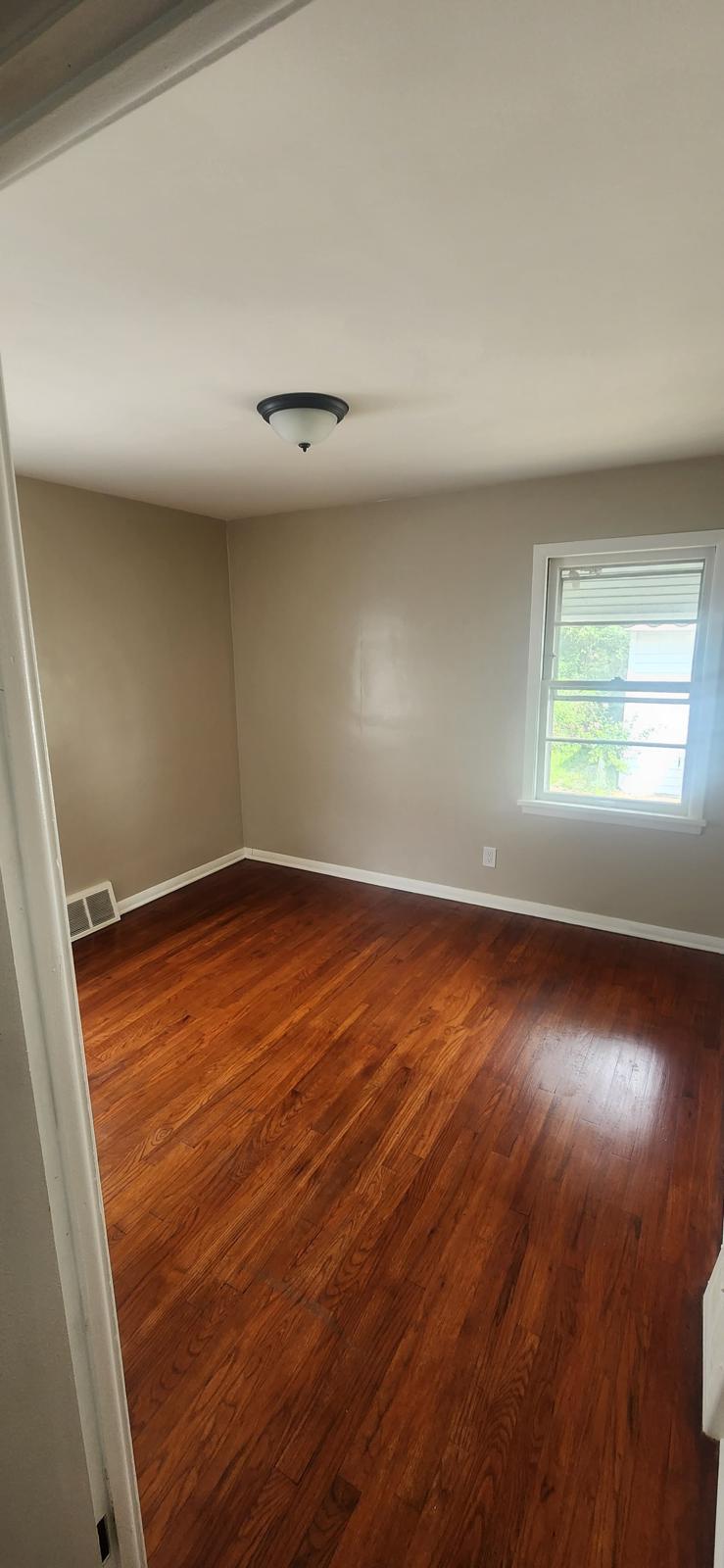 Bedroom with refinished hardwood flooring and warm neutral walls