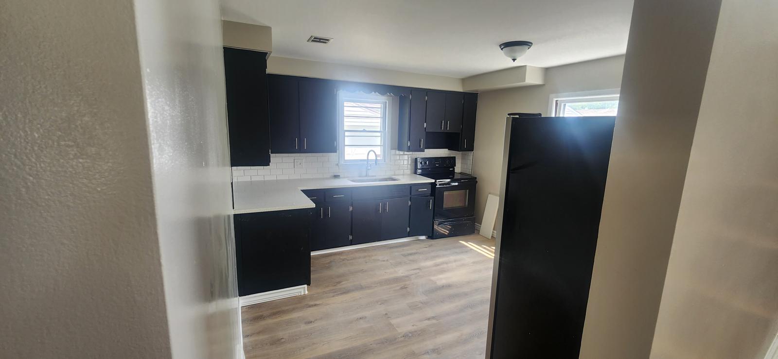 Kitchen with black cabinetry, bright counters and gray flooring