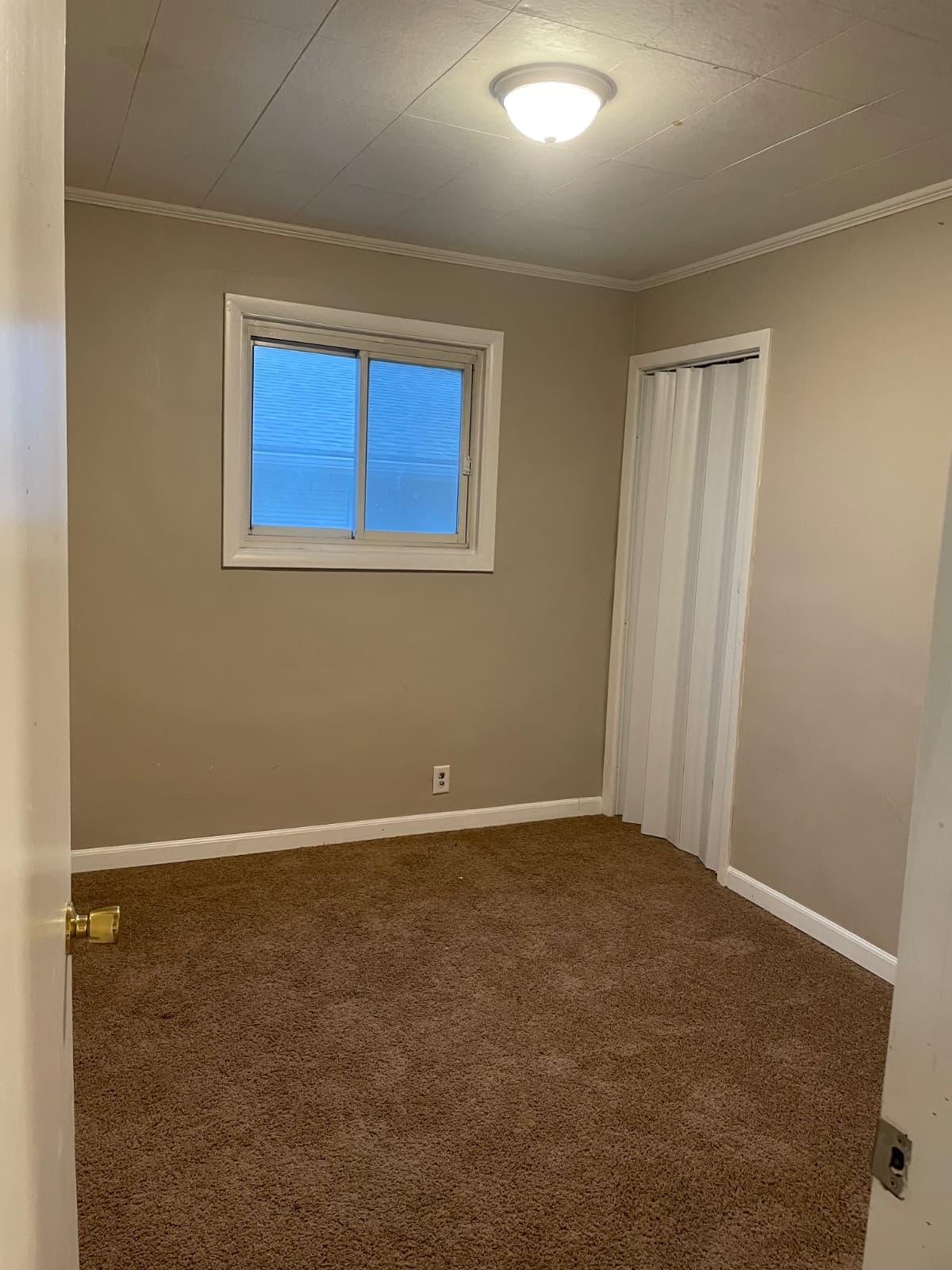 Compact carpeted bedroom prepared for an interior renovation