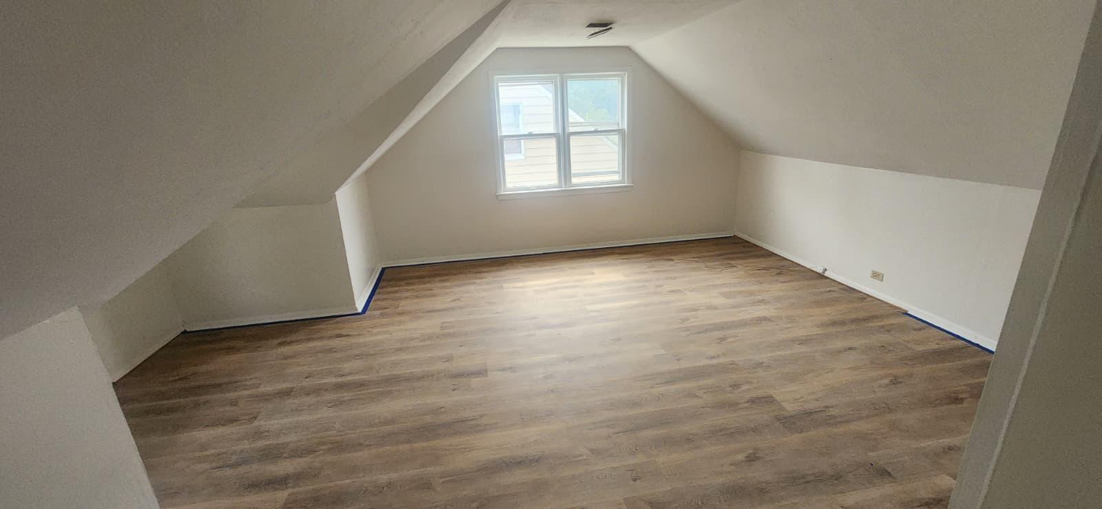 Finished attic room with sloped ceilings and wood-look plank flooring