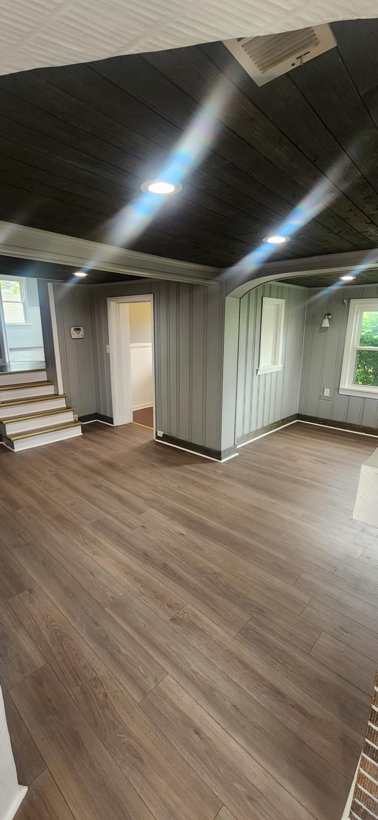 Finished basement with ceiling beams and continuous wood-look flooring