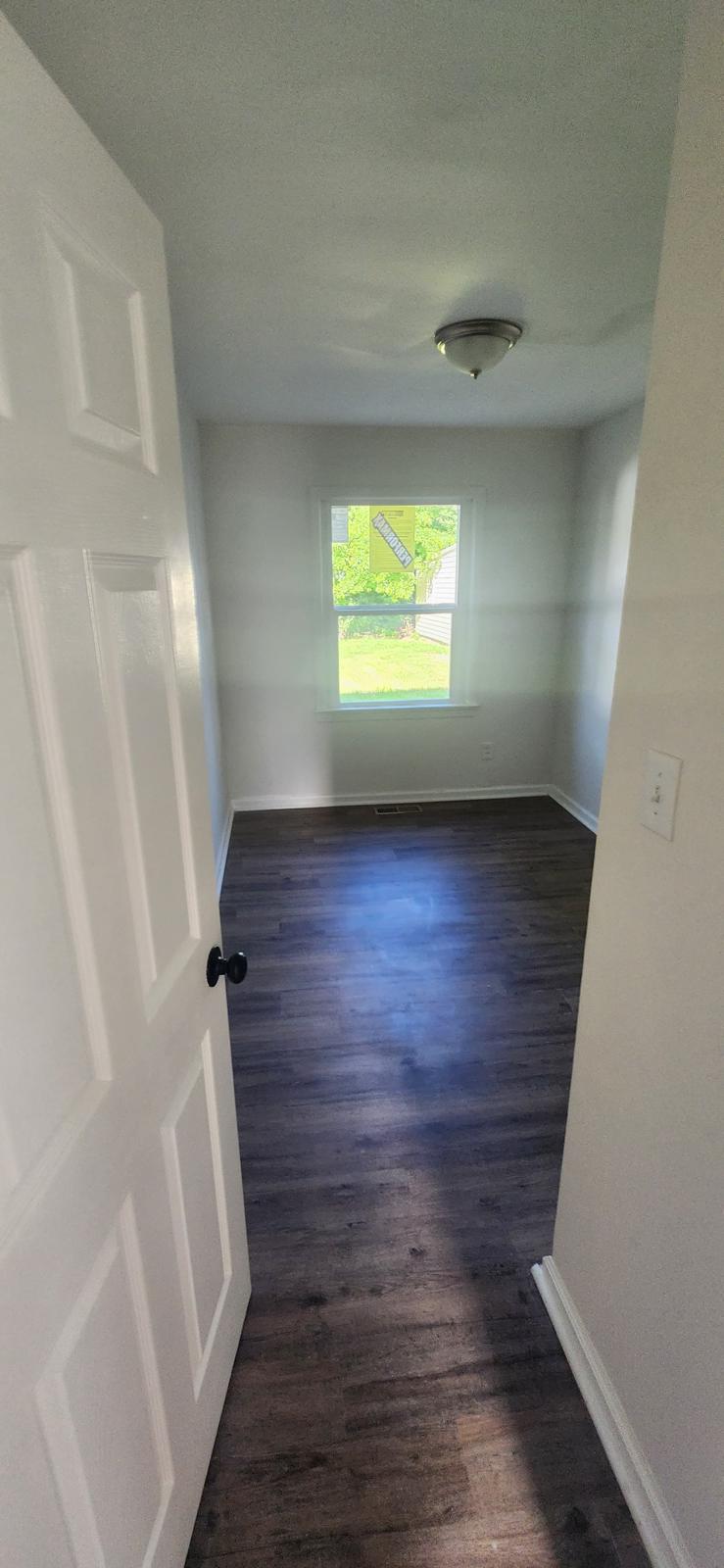 Finished hallway with bright walls, white trim and dark flooring