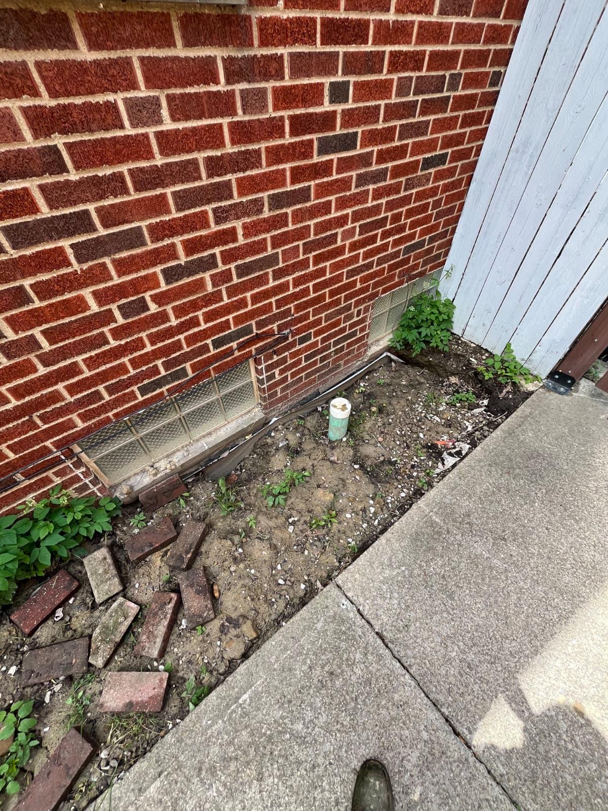 Garden bed beside a brick home before landscaping improvements