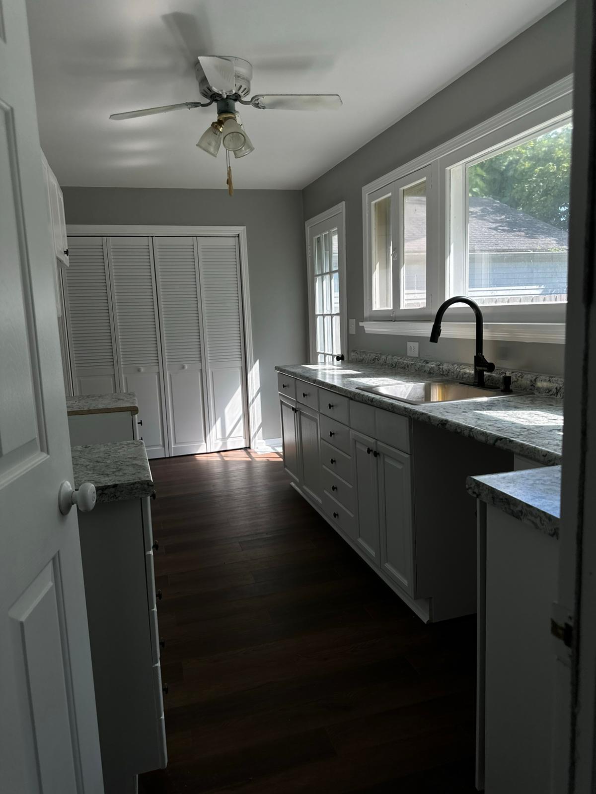 Galley view of a gray kitchen remodel with dark hardwood floors