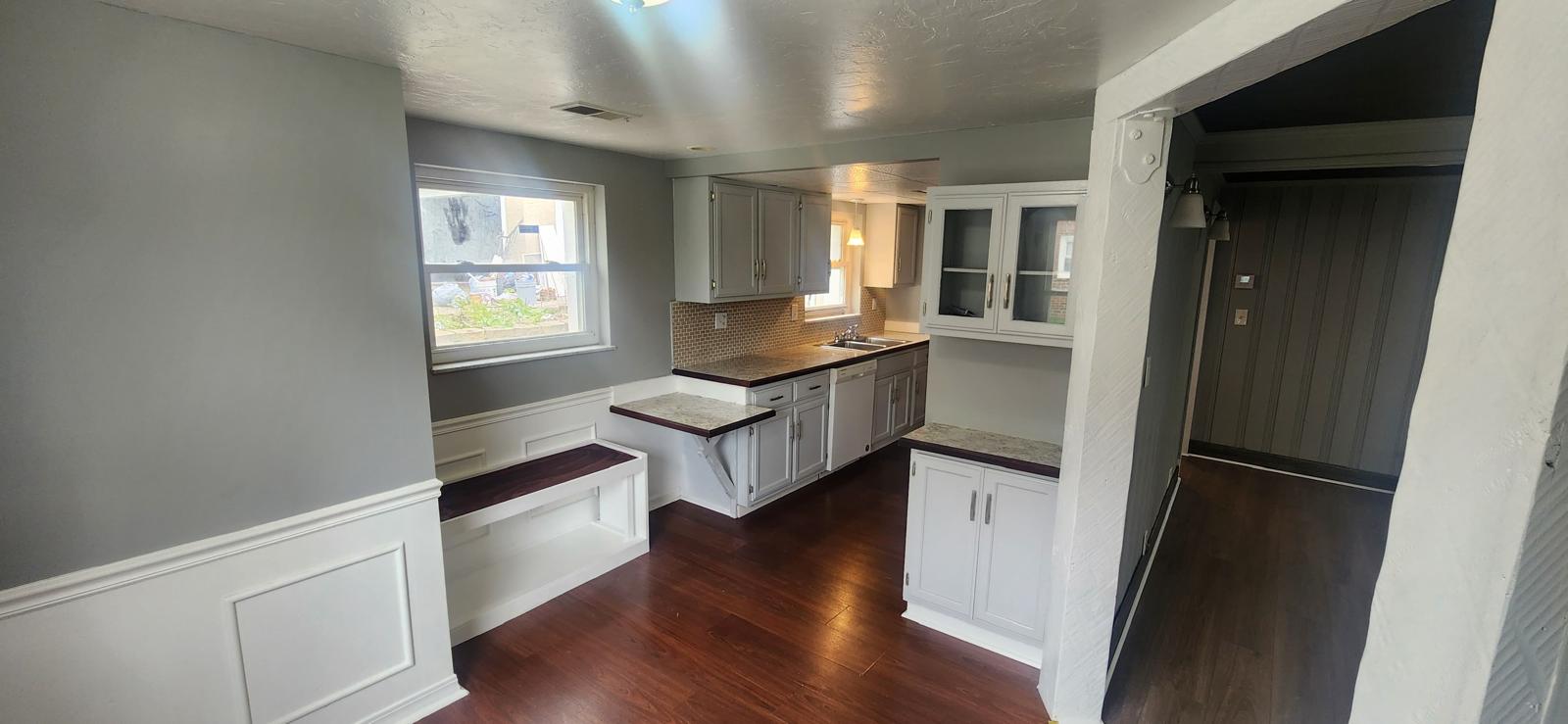 Gray kitchen remodel with stone counters, white cabinetry accents and dark flooring