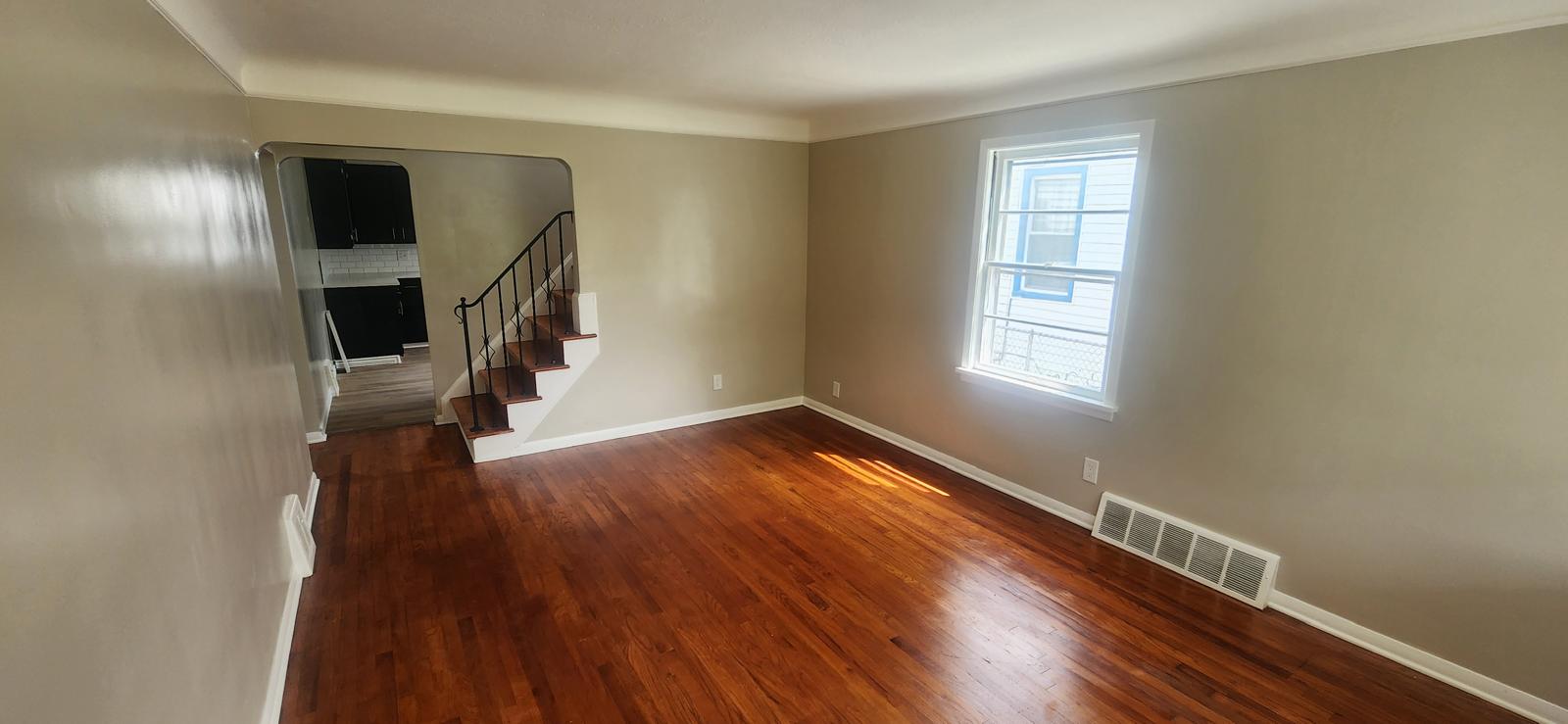 Living room with refinished hardwood floors and an open staircase