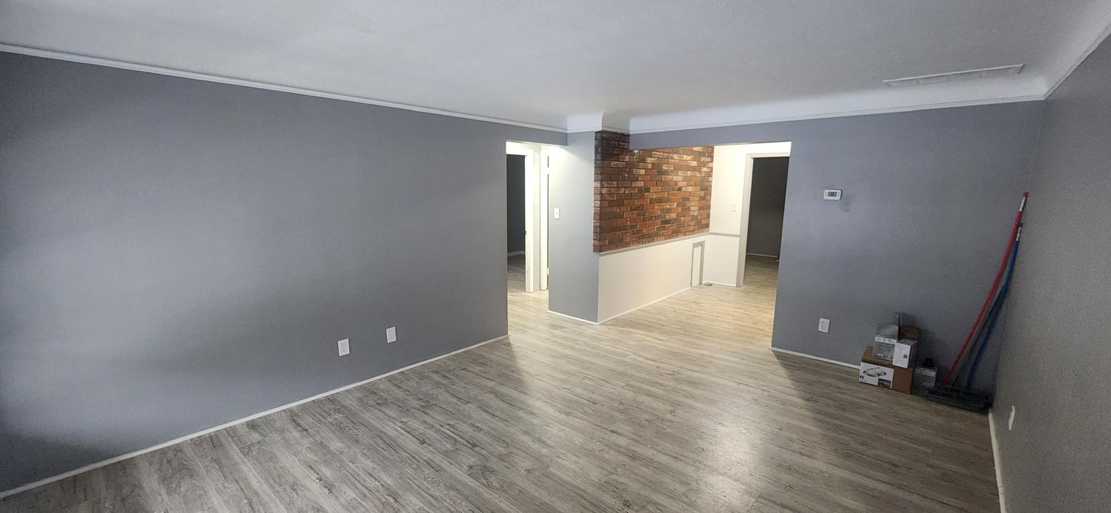 Open-plan lower level with gray plank flooring and freshly painted walls