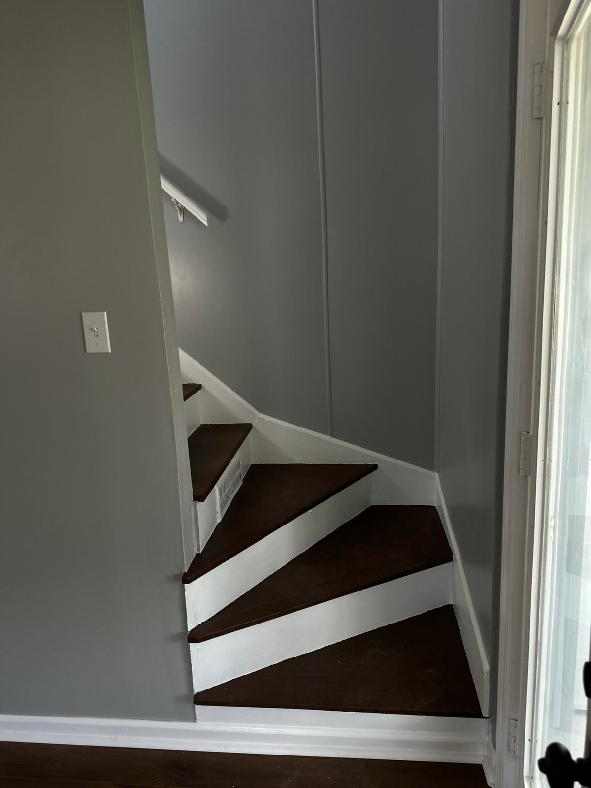 Dark wood staircase refinished beside freshly painted gray walls