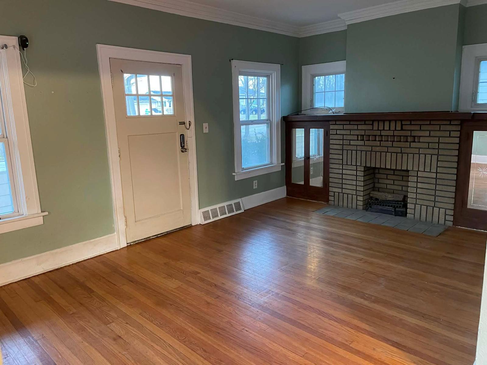 Restored living room with hardwood floors and a brick fireplace
