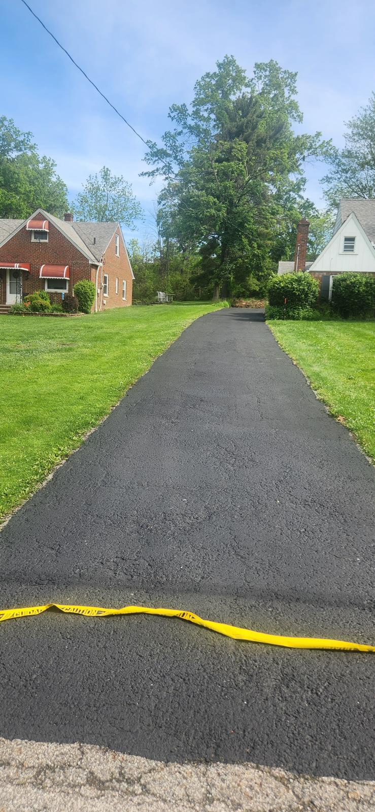 Freshly resurfaced asphalt driveway leading to a detached garage