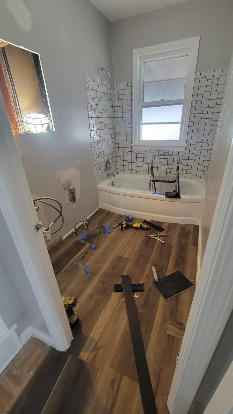 Bathroom flooring installation in progress around the vanity and toilet