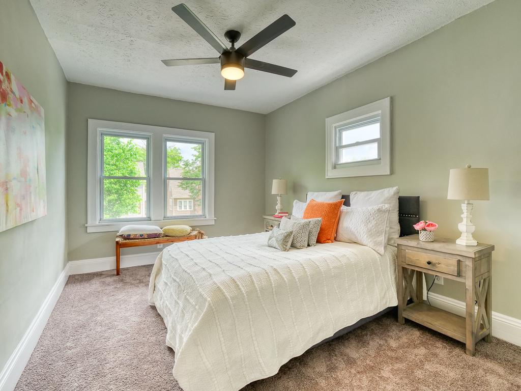 Corner view of a finished bedroom with neutral carpet and white trim