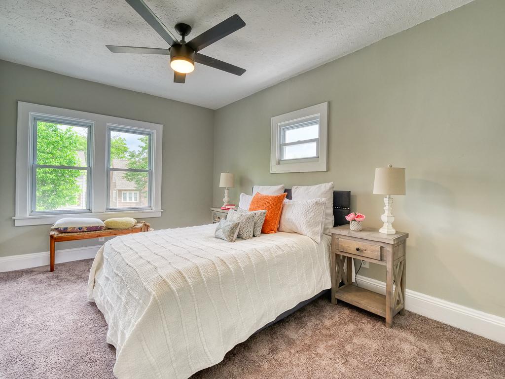 Finished carpeted bedroom with two bright windows and a ceiling fan