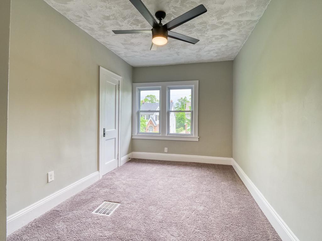 Empty finished bedroom with neutral carpet, light walls and white trim