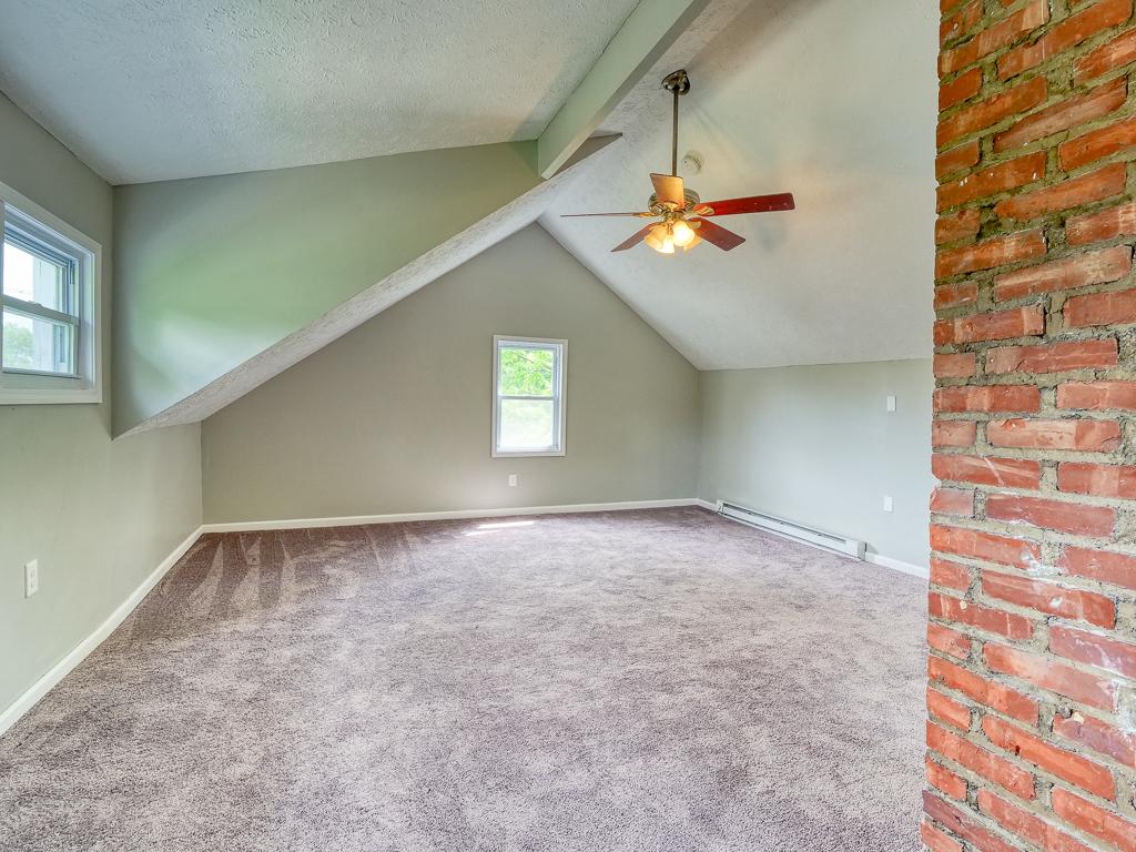 Wide view of a finished carpeted attic with a brick chimney