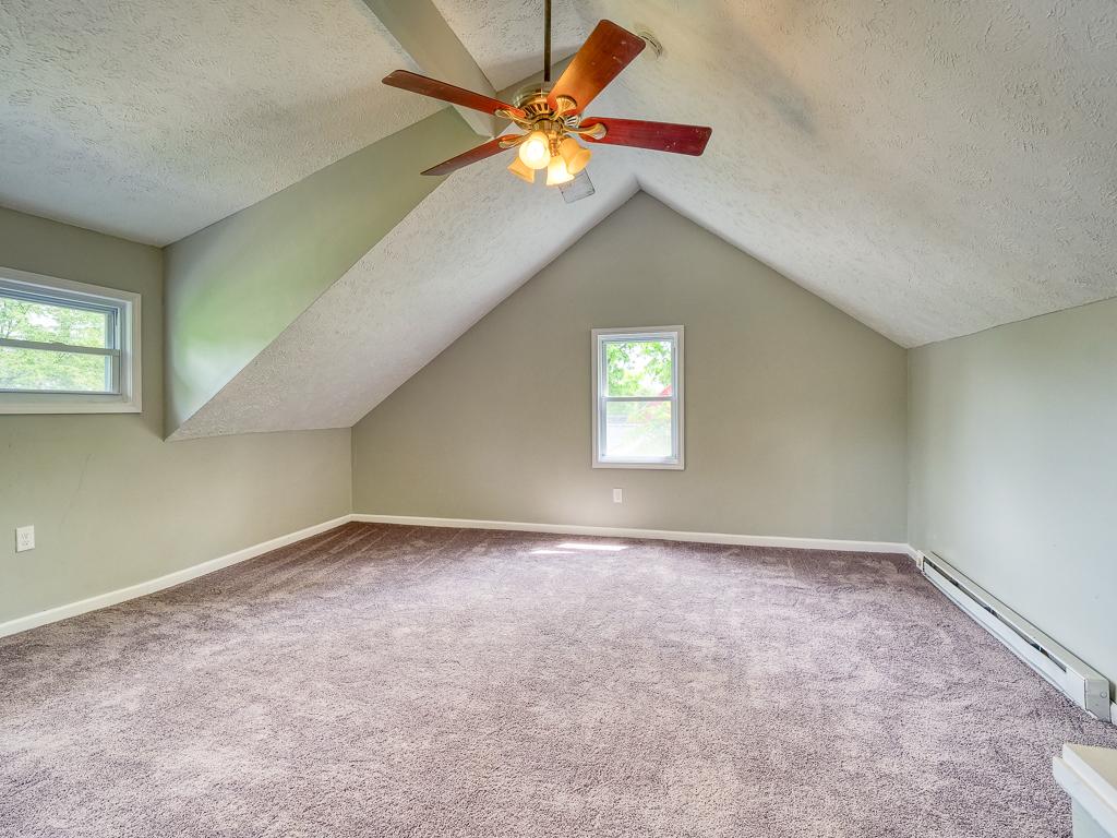 Finished attic room with soft carpet, sloped ceilings and natural light