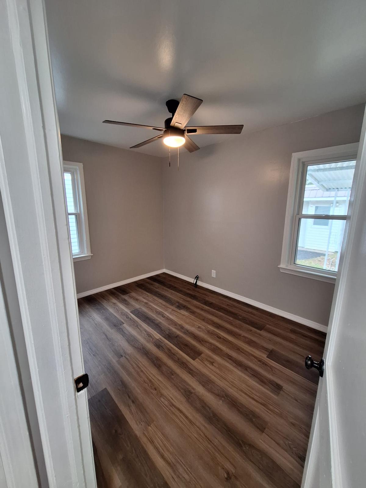 Finished gray bedroom with rich wood-look flooring and white trim