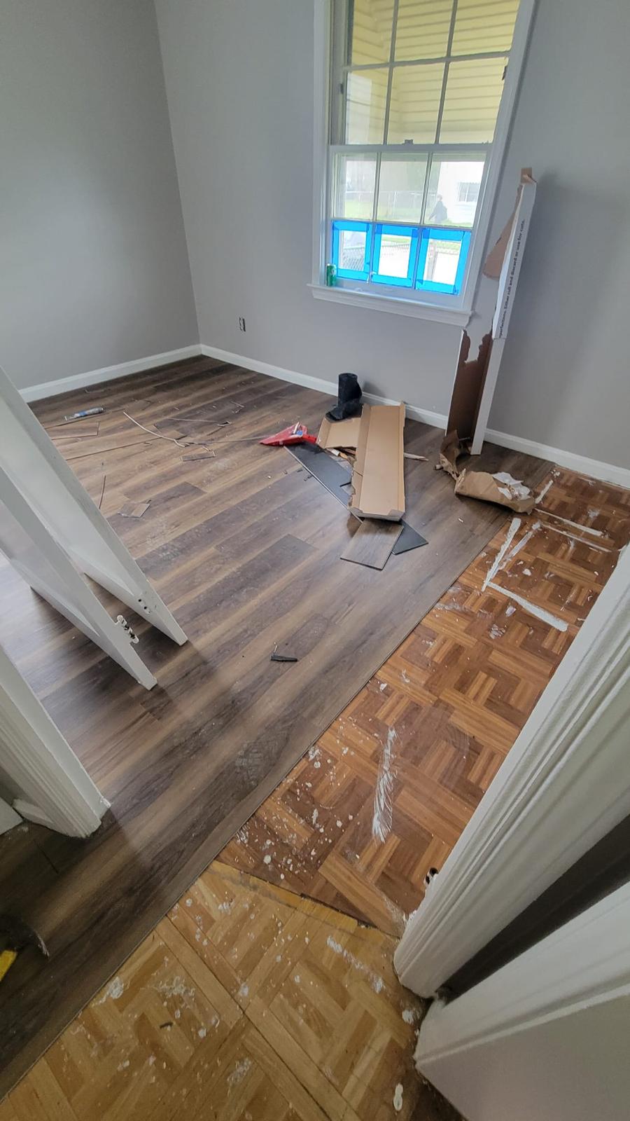 New wood-look flooring being fitted through an interior doorway