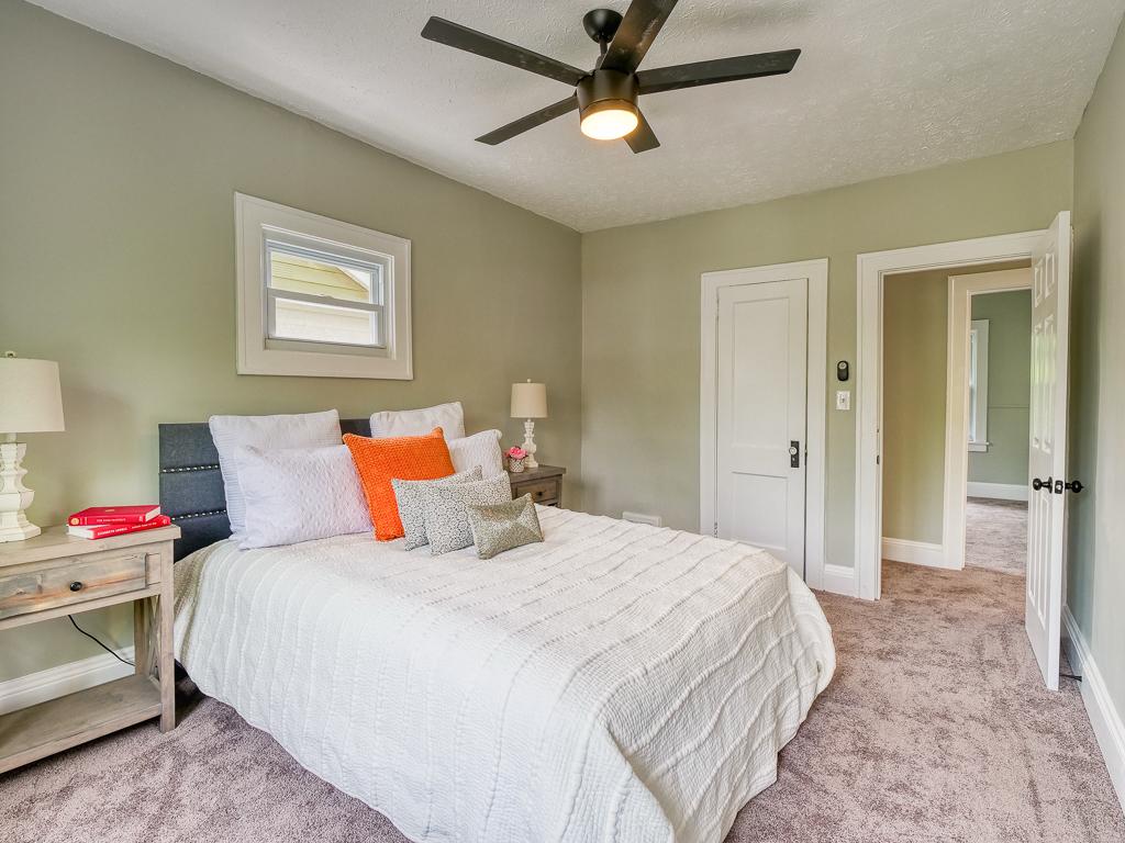 Staged bedroom with new carpet, gray-green walls and a ceiling fan