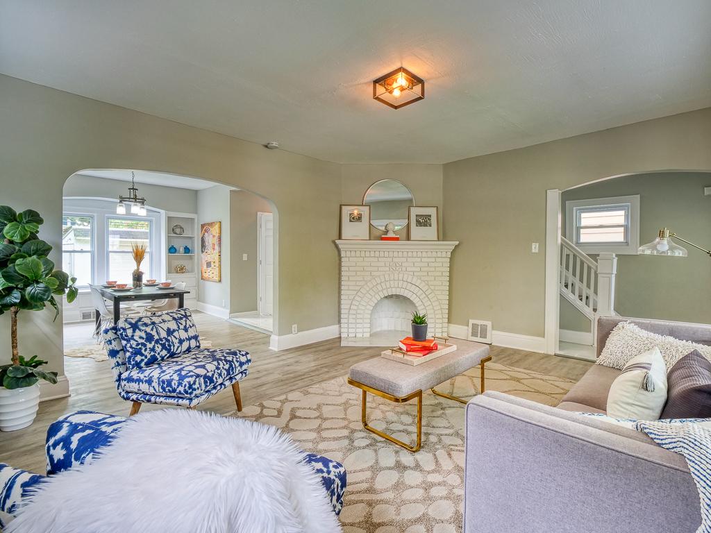 Staged living room with a white brick fireplace and refreshed flooring