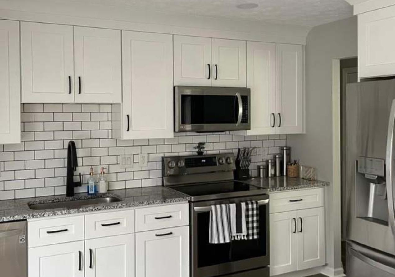 White kitchen remodel with black appliances and a subway-tile backsplash