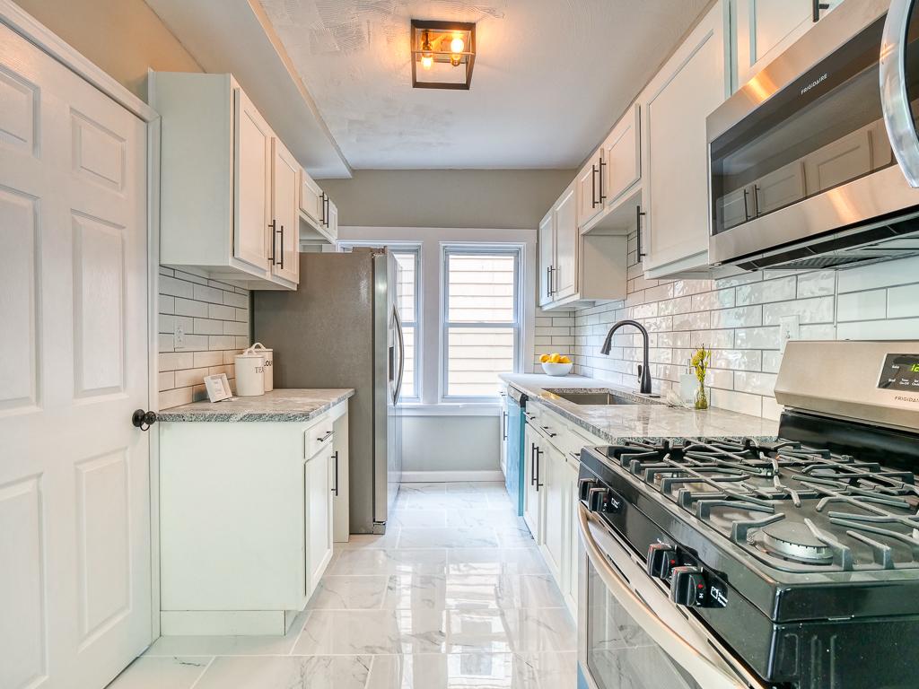 White kitchen remodel with a gas range, microwave and subway-tile backsplash