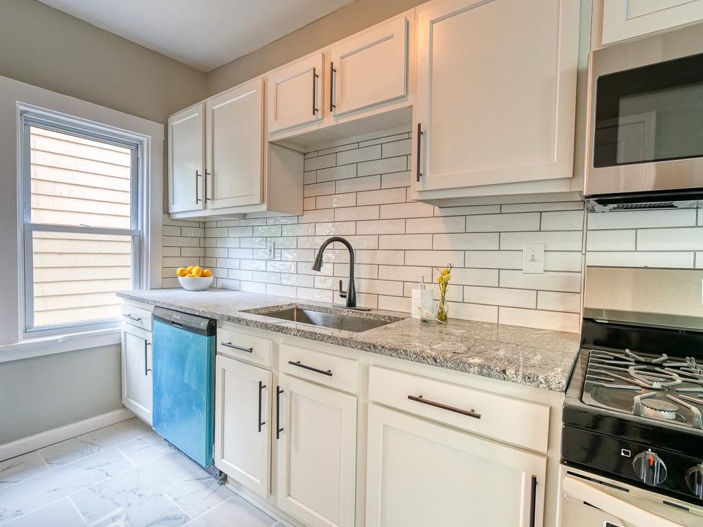 White kitchen remodel with stone counters and a subway-tile backsplash
