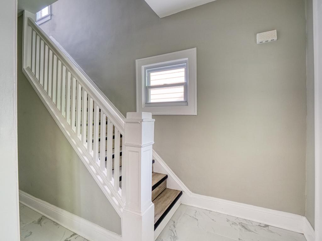 Stair landing with a refinished white railing and bright neutral walls