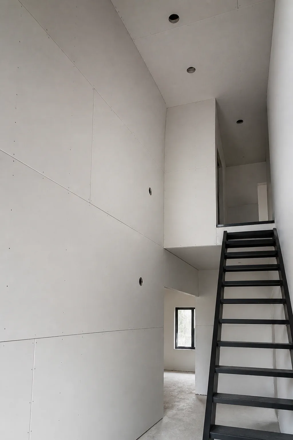Contemporary stairwell drywall installation with clean seams and precise cutouts