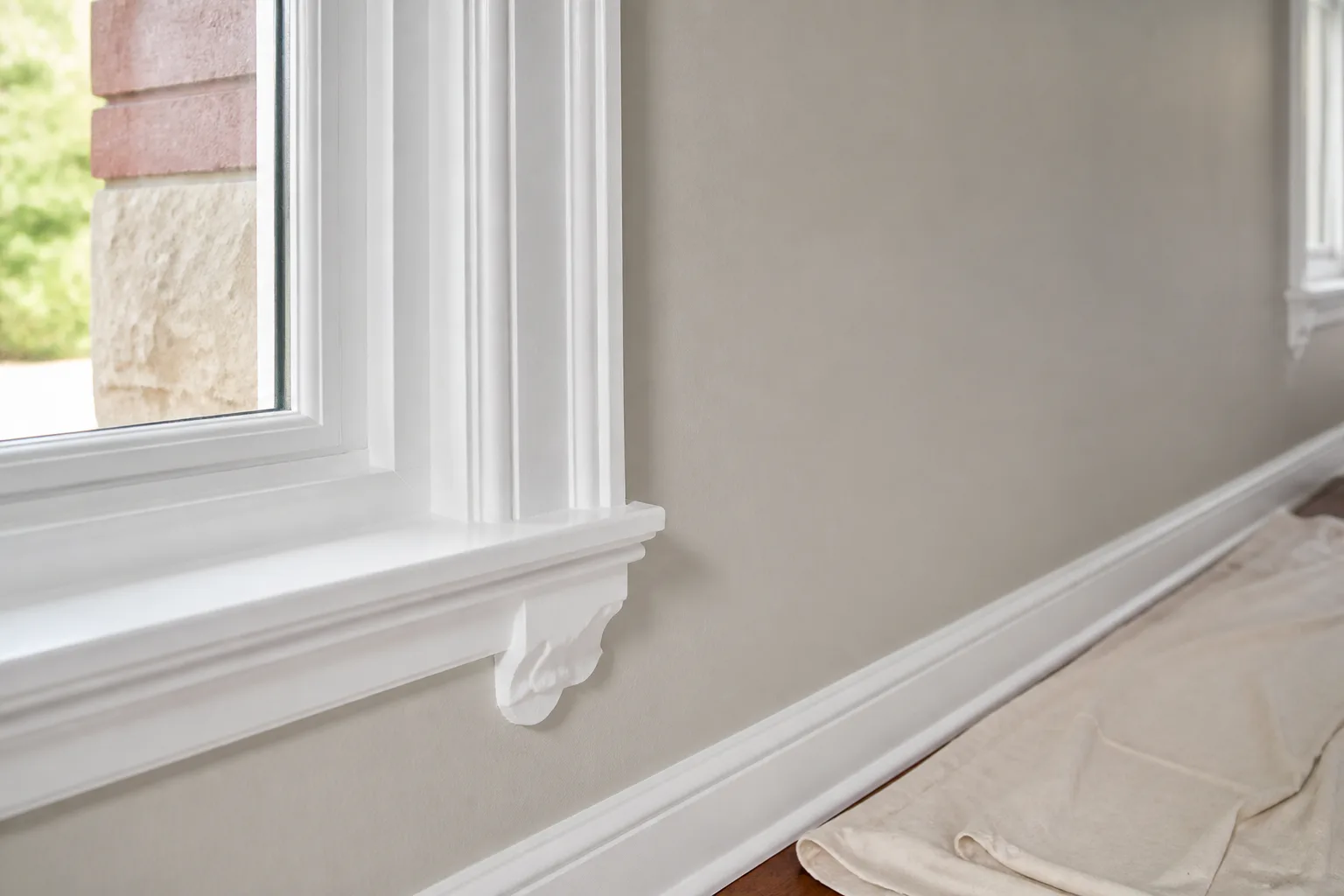 Smooth greige wall and crisp white painted window trim finish detail